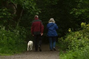 mature couple walking in woods with dog